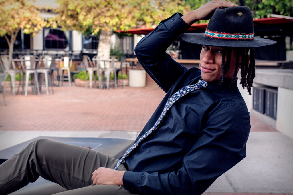 personal branding session with man sitting in chair, leaning back, hand resting on hat